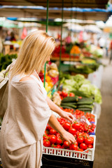Cute young woman buying vegetables at the market