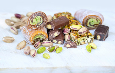 Eastern Turkish sweets with pistachios on a white wooden background. Fragrant baklava, chocolate, sweets with pistachios.