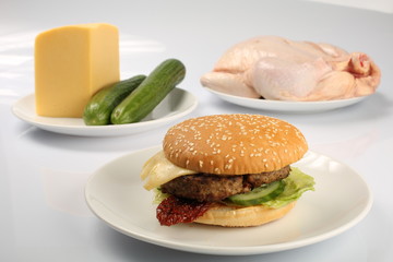 cheeseburger, chicken cutlet, bacon, tomatoes and slices of cheese, dressed with sauce and green salad for a restaurant menu on a white isolated background