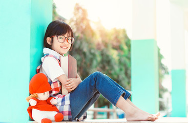 Happy cute little girl with glasses smiling and holding book