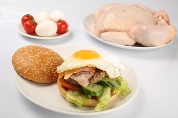 cheeseburger, chicken cutlet, bacon, tomatoes and slices of cheese, dressed with sauce and green salad for a restaurant menu on a white isolated background