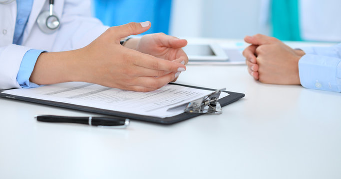 Doctor and patient discussing something, just hands at the table, white background