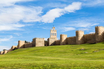View of the medieval city walls surrounding the city of Avila, Spain, and the green lawn in front of Puerta del Carmen. Called the Town of Stones and Saints, Avila is a UNESCO World Heritage Site © giusparta