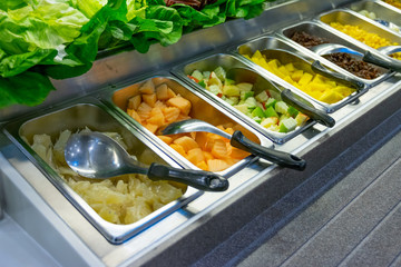 Freshly cut vegetables are lined up in a tray for sale as a vegetable salad in the supermarket.