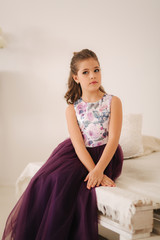 Naklejka premium Beautiful girl in a purple dress and flower blouse posing for a photographer