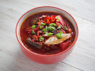Bowl of Ukrainian borscht on a white wooden table.