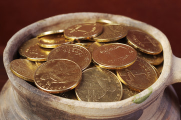 Gold coins in a clay pot. Close-up. Ukrainian hryvnia.