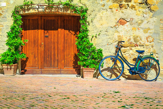 Fototapeta Tuscany street with flowery entrance and retro bicycle, Pienza, Italy