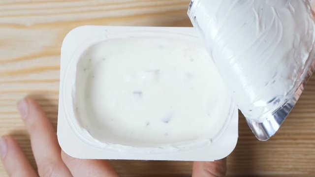 Opening a jar of yogurt.