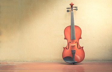 Wooden violin with old wall and wood floor.
