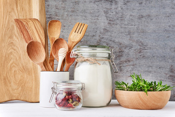 Kitchen background with cutting board, wooden cutlery and rosemary on a white table