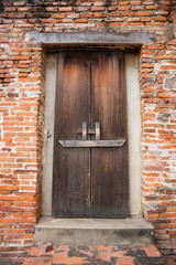 Ancient wooden door on brick wall.