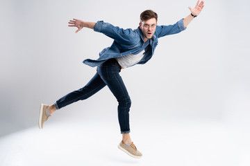 Full length portrait of a happy excited man jumping and looking at camera isolated over white background.