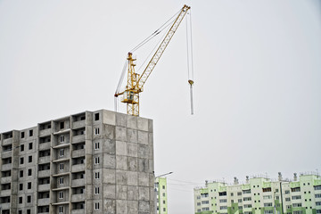 Multi-storey apartment building and a crane in the final stage of construction against the background of constructed houses