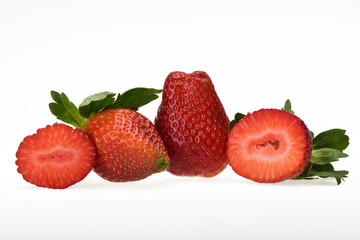 Two ripe red strawberries with green leaves and one cut on a neutral white background