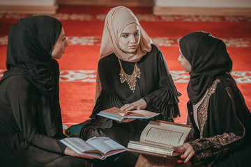 Three muslim girls reading Quran in mosque