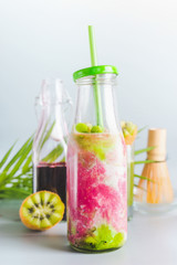 Bottle with matcha fusion latte and ingredients: matcha, red berries juice, kiwi fruits and milk on...