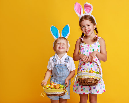 Naklejki funny happy child boy with easter eggs and bunny ears on yellow.