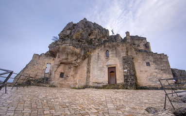 Fototapeta premium Matera, Basilicata, Puglia, Italy - View of the church of Madonna de Idris ( Chiesa Rupestre di Santa Maria di Idris ) in the rock. Cave church in Sassi old town. Montirone hill