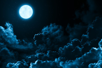 Bright full moon in the mystical midnight sky with stars surrounded by dramatic clouds. Dark...