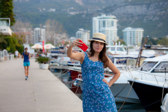 Young travelling woman in hat taking selfie photos over summer sunny mediterranean city