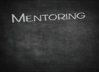 Obraz premium Mentoring - handwritten with white chalk on a blackboard
