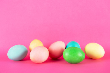 Bunch of blank painted Easter eggs of different pastel color isolated on bright pink background with a lot of copy space for text. Front view, flat lay, close up.