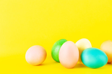 Fototapeta na wymiar Bunch of blank painted Easter eggs of different pastel color isolated on bright yellow background with a lot of copy space for text. Front view, flat lay, close up.