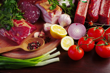 Sausage, salami, ham and vegetables on the kitchen board