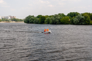 Two workers of the emergency service hurrying down the wide river in the summer