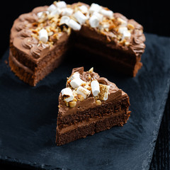 Chocolate cake with a cut piece and blade on black background, closeup