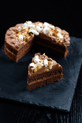 Chocolate cake with a cut piece and blade on black background, closeup