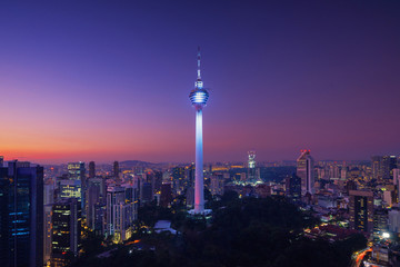 Fototapeta premium Menara Kuala Lumpur Tower w nocy. Widok z lotu ptaka centrum Kuala Lumpur, Malezja. Dzielnica finansowa i centra biznesowe w azjatyckim mieście miejskim. Wieżowiec i wieżowce w południe.
