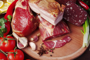 Smoked meat and ham with vegetables on the kitchen board