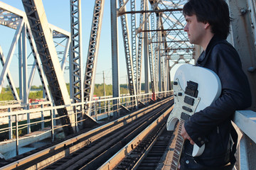 Man with an electric guitar in the industrial landscape outdoors