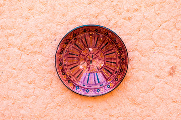 Colorful hand made  traditional ceramic plate on clay brown wall in Morocco.