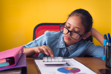 Cute girl wearing glasses is boring with hard work on the desk isolated on yellow background.
