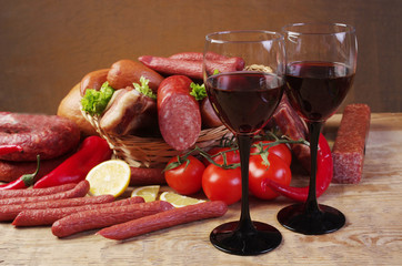 Two glasses of red wine, a bottle and meat products