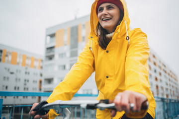 Girl in yellow raincoat riding bicycle on rain day