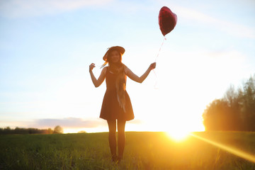 A girl in a hat on a walk in the park. A girl with a basket walks in the spring. A girl is walking along the road at sunset.