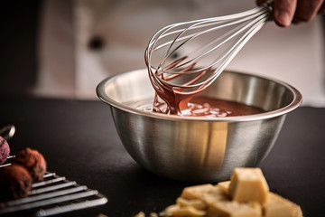 Chef holding a whisk with melted chocolate