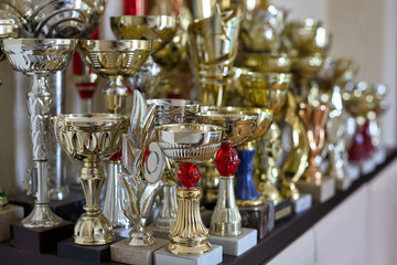 Sports cups, trophies on the shelf, golden and silver. Victory concept. Indoors, copy space.