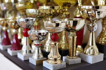 Fototapeta na wymiar Sportive trophy cups, trophies on the shelve, golden and silver. Victory concept. Indoors, copy space.