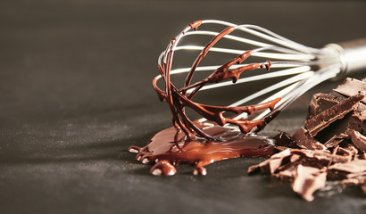 Melted dairy chocolate dripping off an old whisk
