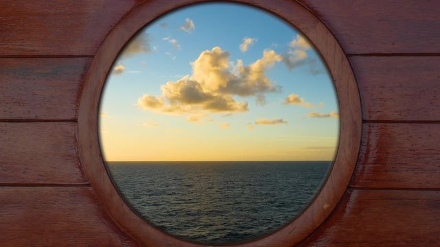 Looking outside through a porthole of a cruise ship to the sea