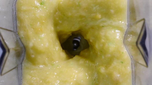 Making fresh fruits shake in blender. Pineapple ananas fruit slices mixing in slow motion. Close up top view. Healthy food, dieting