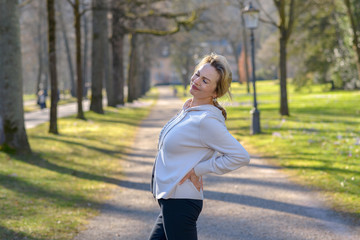 Woman holding painful back in park