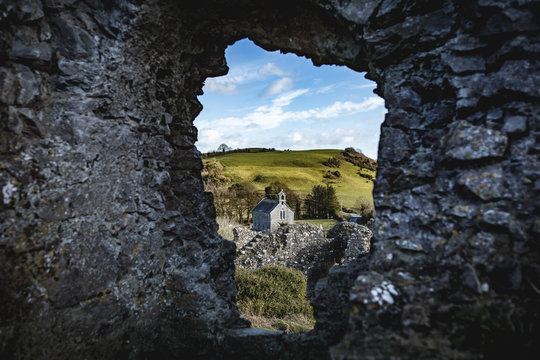 A small church seen through the Hole in the Wall (most likely a window in its time) at the ruins of Rock of Dunamase, in county Laois, Ireland  