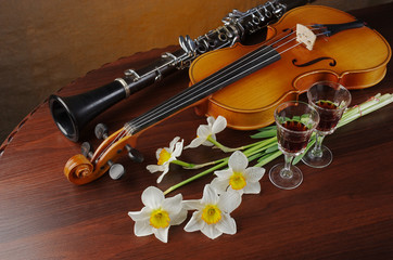 Violin, clarinet and bouquet of flowers on a wooden table.
