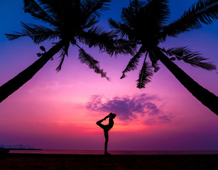 Beautiful young woman practic yoga at the beach. Early morning exercise. Sunrise
